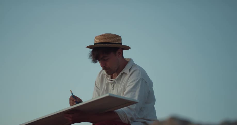 A man is sitting outdoors and drawing