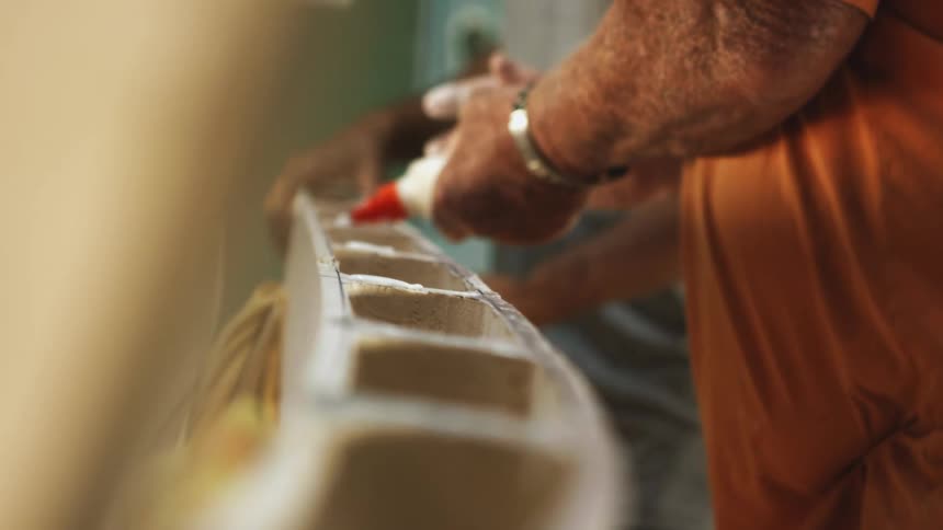 Two men apply and pat down wood glue on unfinished wood