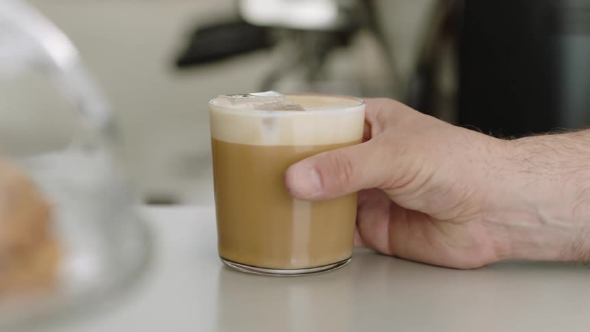 A man takes a glass of iced coffee off of a tabletop