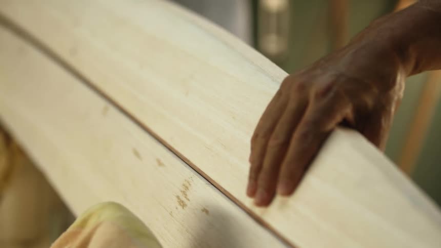 Carpenters assembling the parts of a surfboard inside a workshop