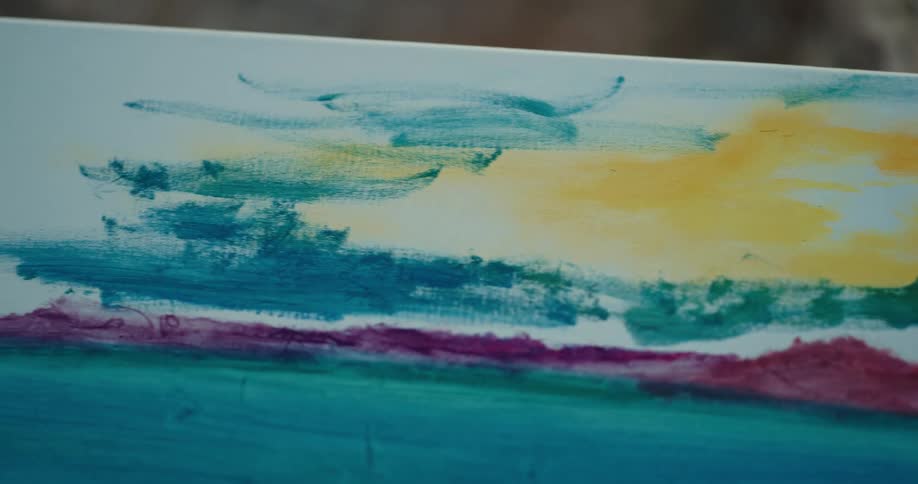 A person painting on a canvas with a paintbrush with a cliff in the background