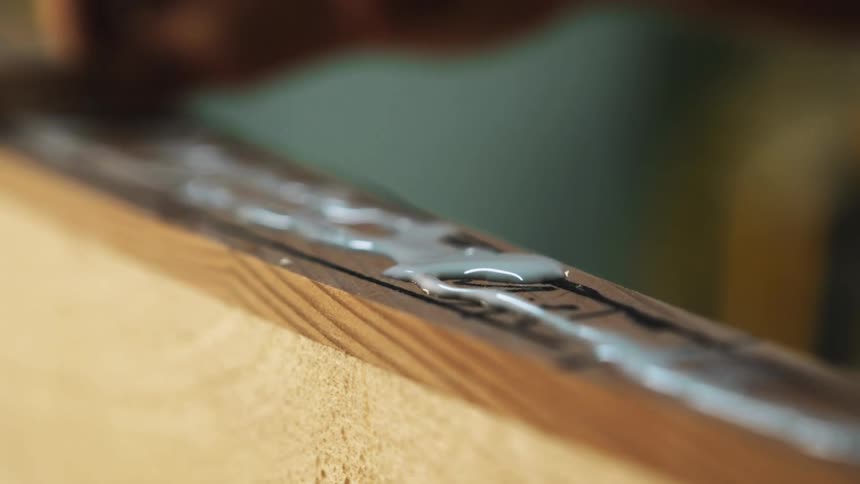 A person that is staining a piece of wood in a shop
