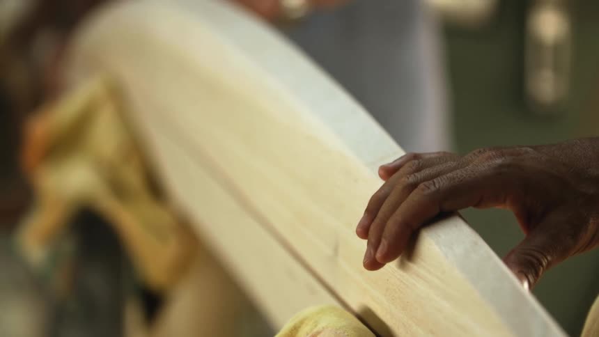 Carpenter assembling the halves of a surfboard in a workshop