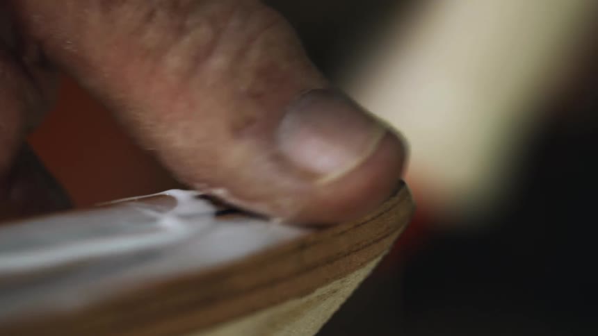 A carpenter uses his finger to smear glue on wood