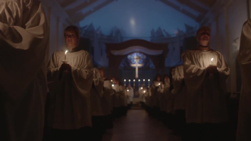A church choir performs while holding candles