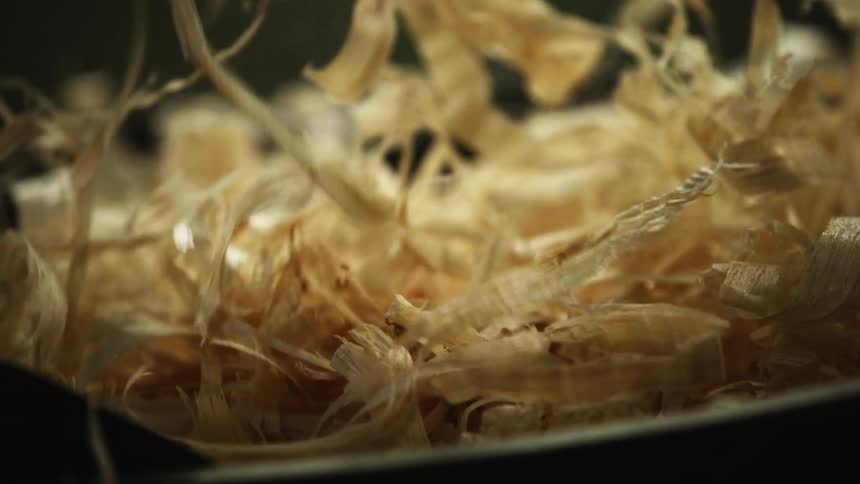 Man picking up wook chips and shavings from a container