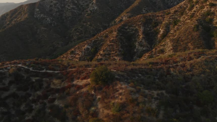A person riding a bicycle on a dirt path with a mountain range in the background