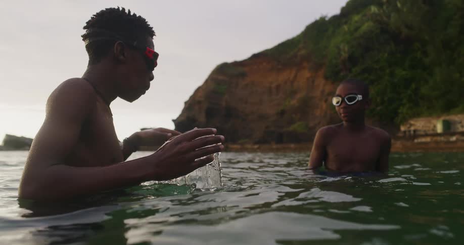 Two friends standing on the ocean near the coast learning to dive