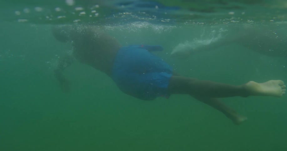 Two boys swimming underwater with bubbles