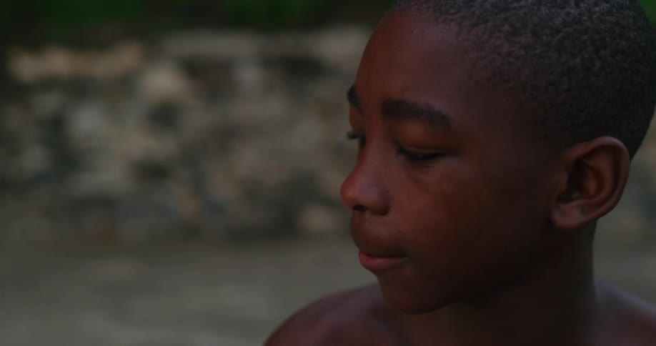 A boy sitting outside nodding his head as he listens to another