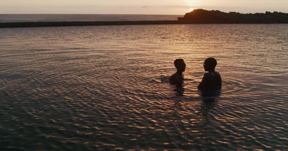 Two people chat as they float in chest high water in a lake