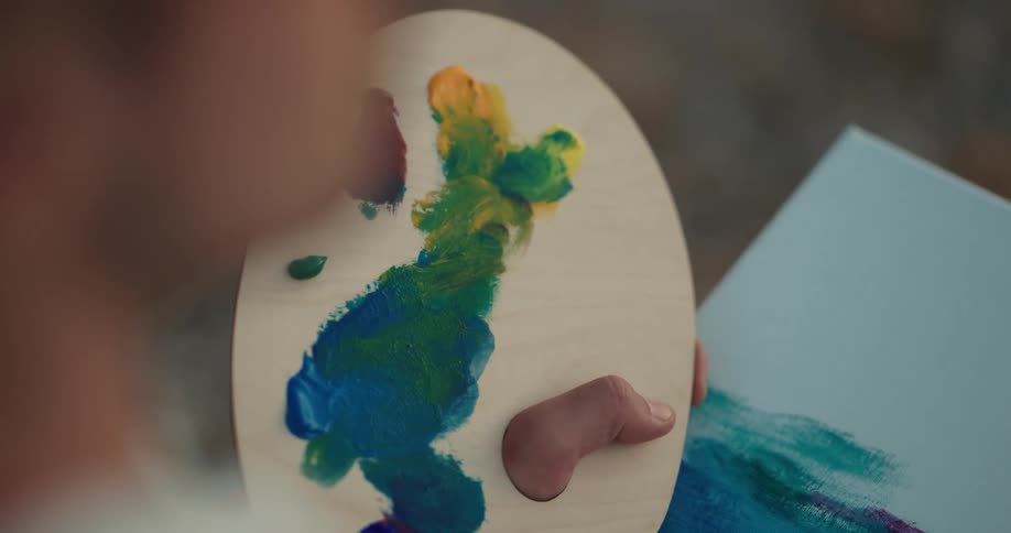 Painter painting with oil over canvas using a brush and a pallet