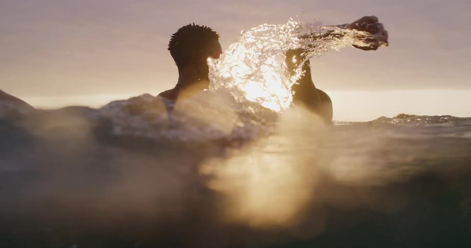 A boy stands in a lake and teaches another boy how to swim