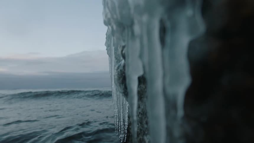 Waves crash against an icy ledge