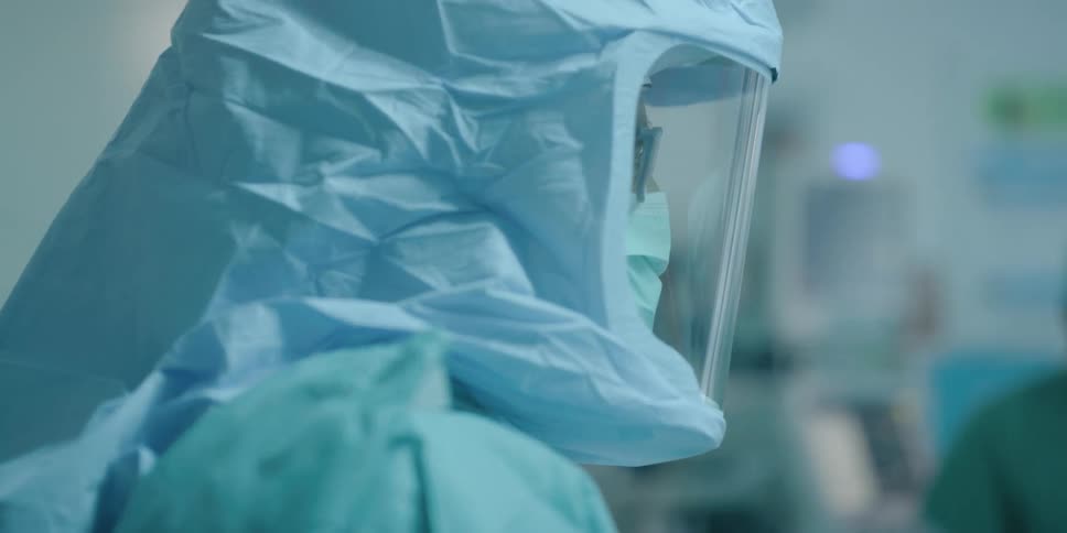 A man with a mask has personal protective equipment placed on him