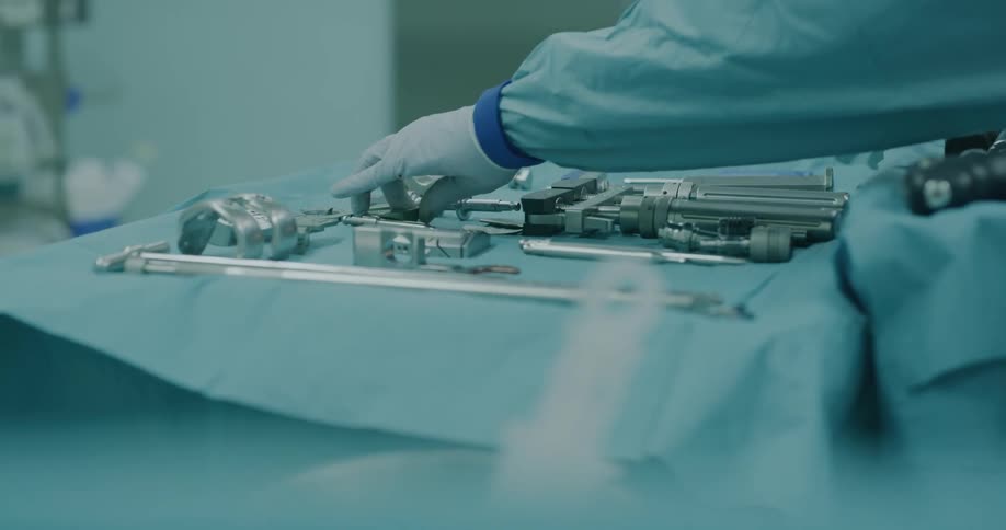 Surgeon picks up surgical equipment from a table on a surgery room