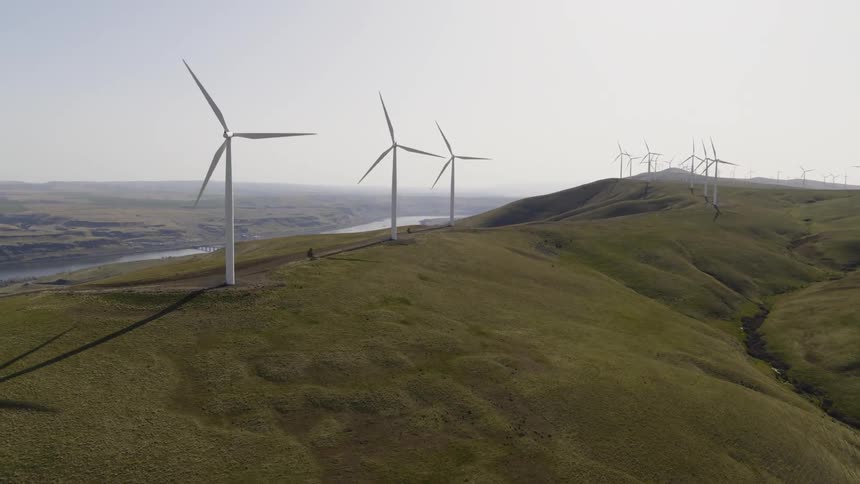 Wind turbines dot a beautiful hillside as they generate power