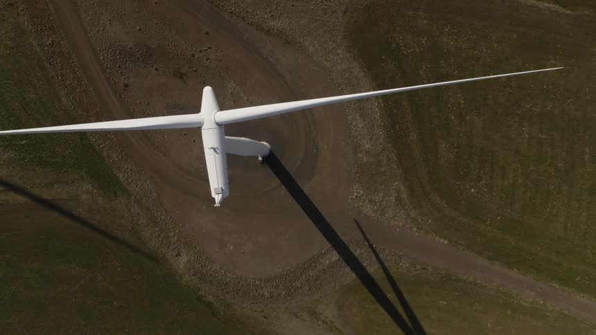 Descending towards the spinning blades of a wind turbine from above