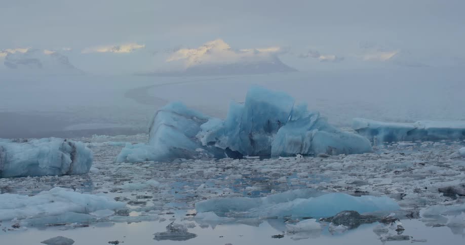 Ice covers water stretching to the horizon under a cloudy sky