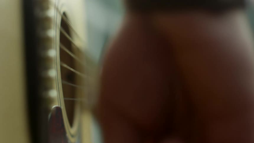 Musician strumming the strings of an acoustic guitar
