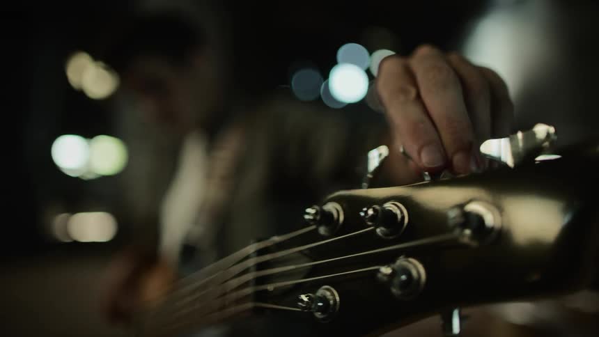A man is tuning his guitar