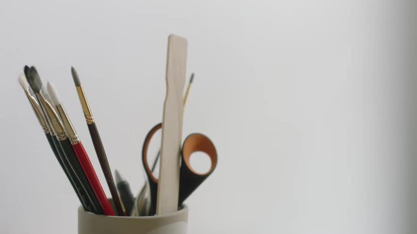 A view of a cup full of paintbrushes and other art tools