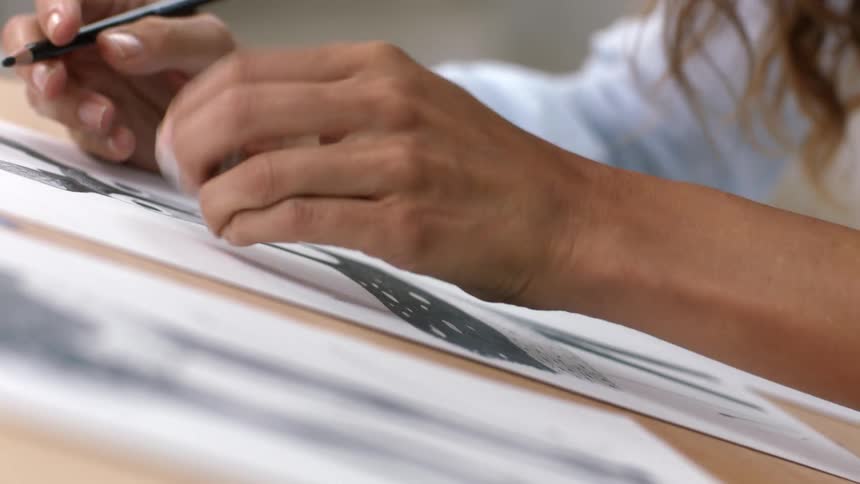 Designer drawing with pencil over paper on a table uses an eraser