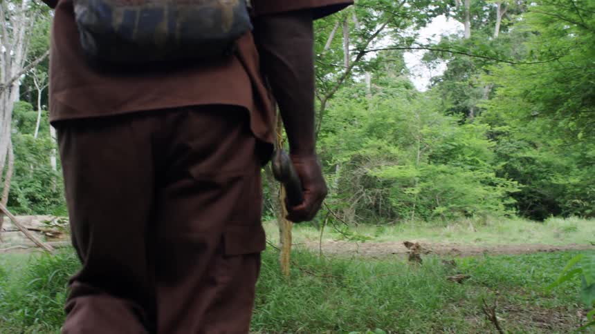 A man is carrying a knife as he hikes in the woods