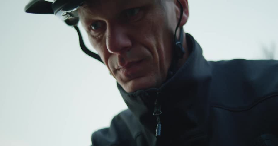 Man wearing a bicycle helmet standing outdoors at evening