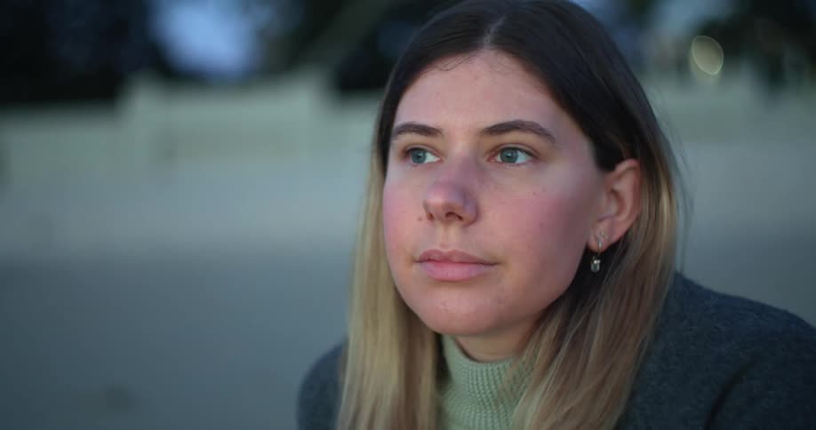A young woman looks around at her surroundings while sitting outdoors