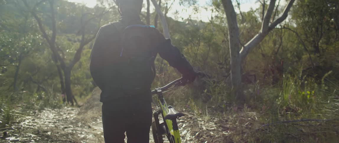 Man pushing bike in forest