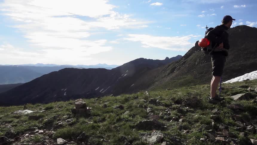 Hiker standing in a field full of grass and rocks