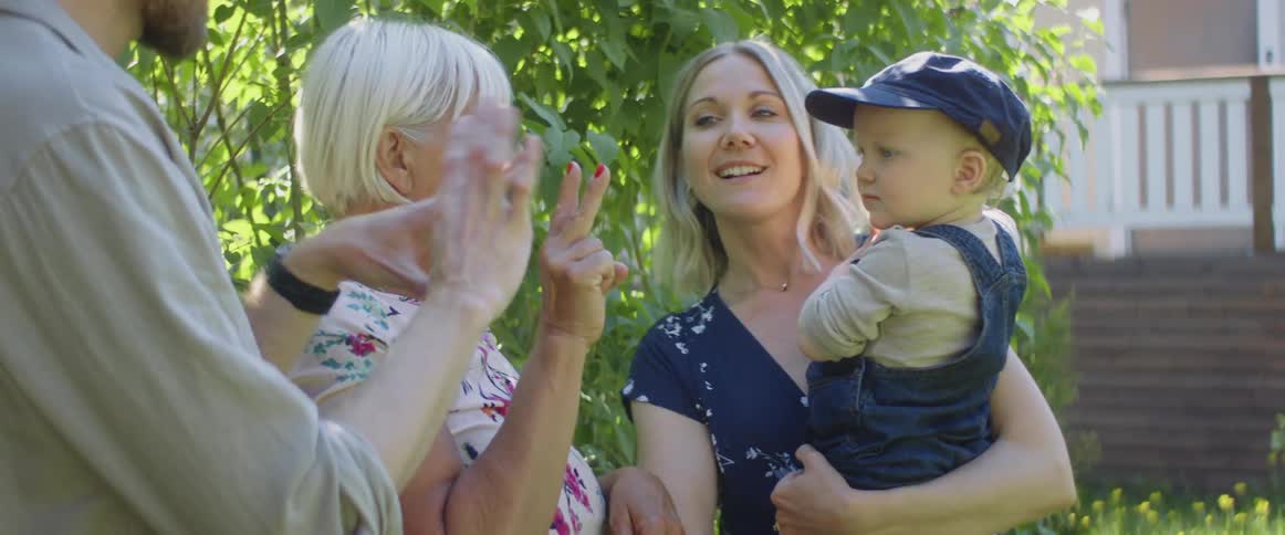 Family stand in yard near house smiling gesturing and talking