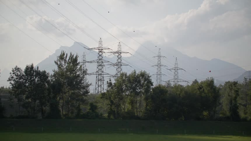 Utility towers high above the trees with mountains on the horizon