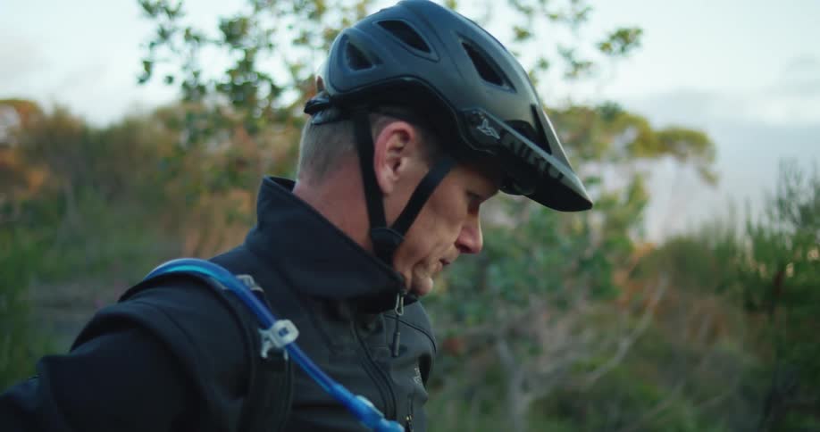 A man with a helmet putting on a backpack