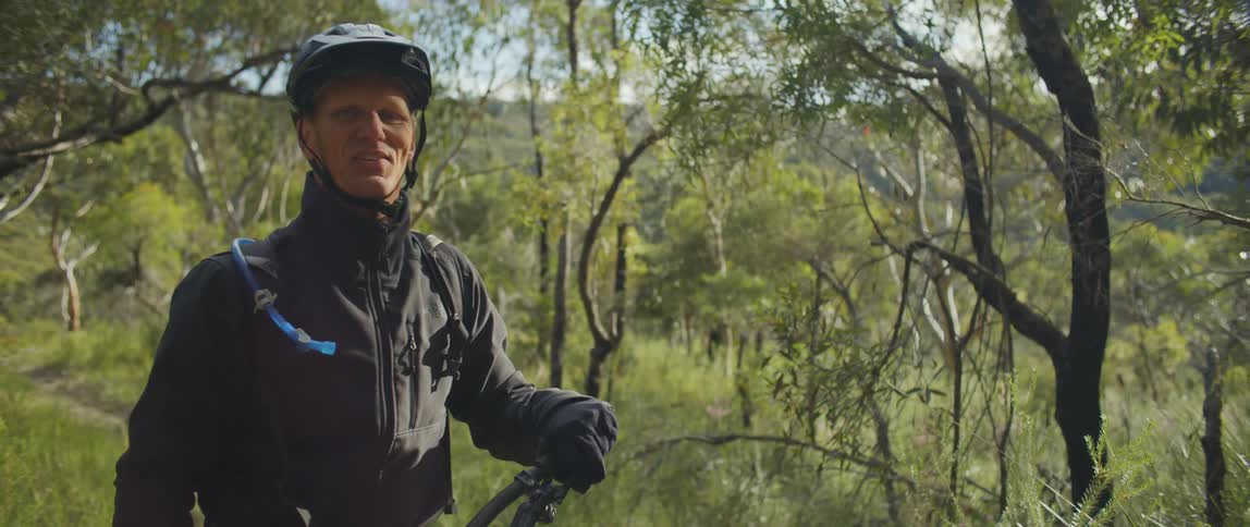 A man walking with a bicycle through a forest