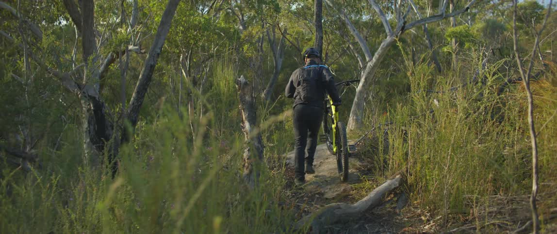 A man walking a bike on a trail