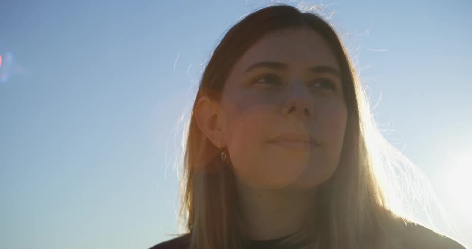 A woman looks around outside on a clear day