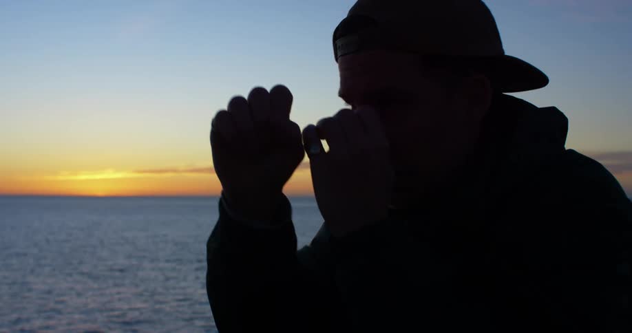 A man is exercising outdoors by the ocean at dusk