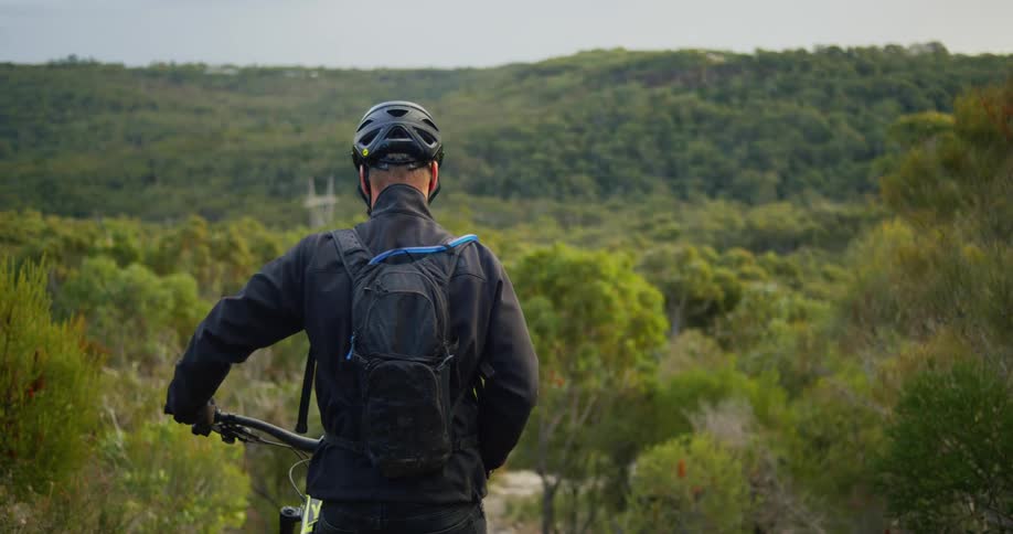 A man walking a mountain bike through shrubs in nature