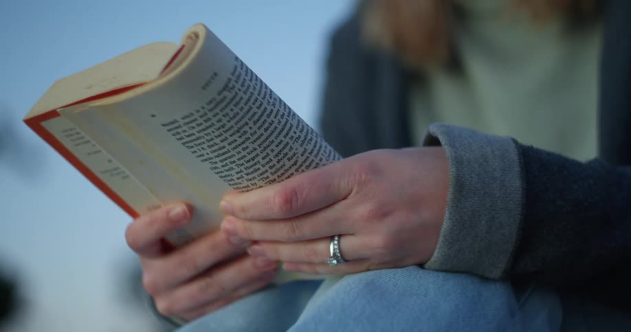 A woman sitting outside reading a book