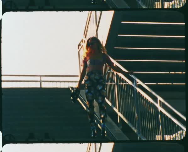 A young woman descends a cement staircase outdoors during the day