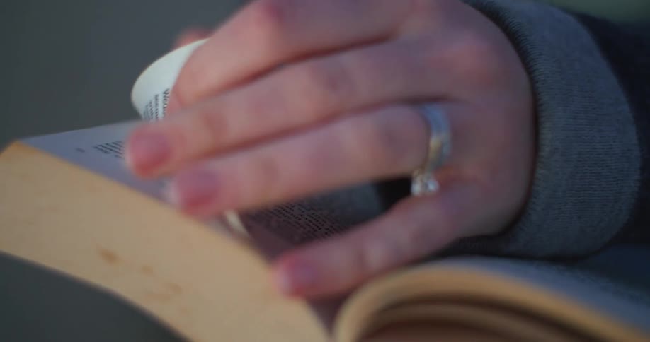 A person with a ring on their finger reading a book and turning the pages