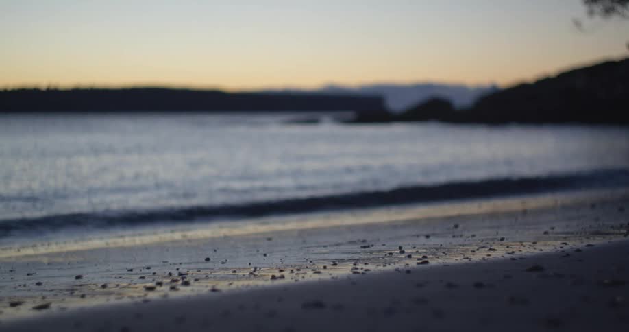 Small waves wash onto the beach at sunset