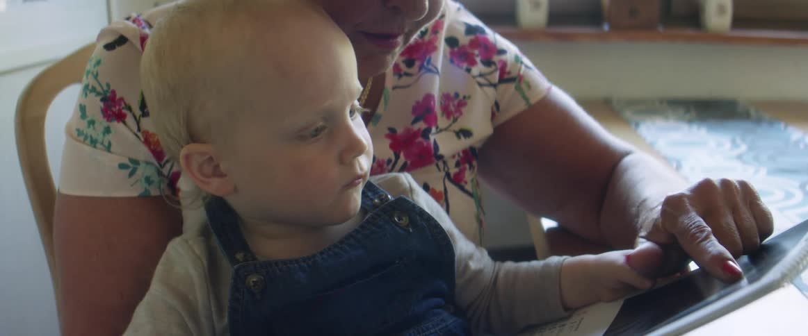 Grandmother showing pictures to her baby grandson at home