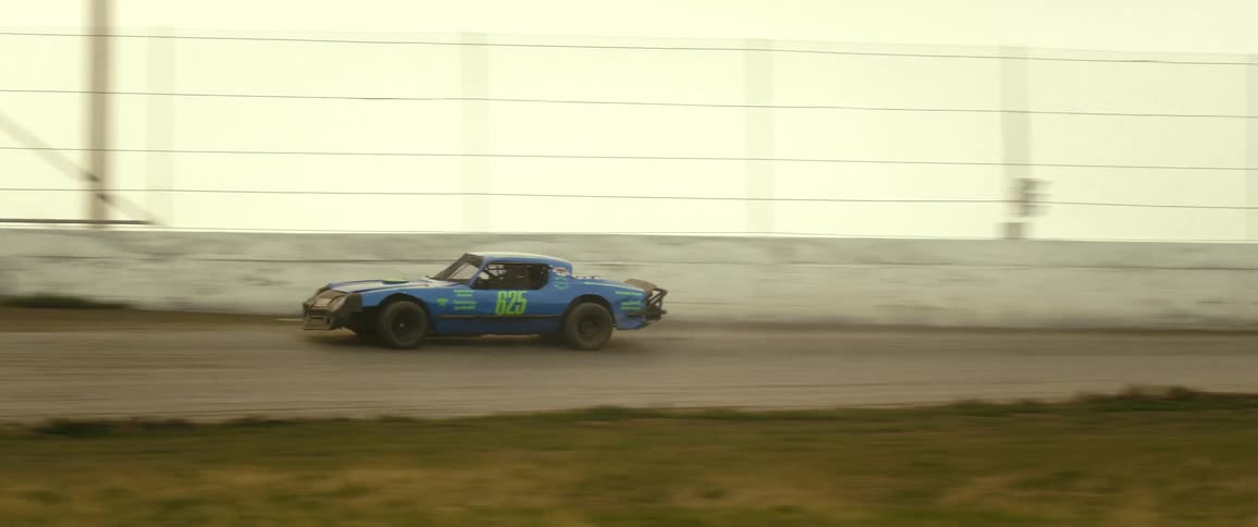 A race car attempts to drive around an old dirt race track before spinning out