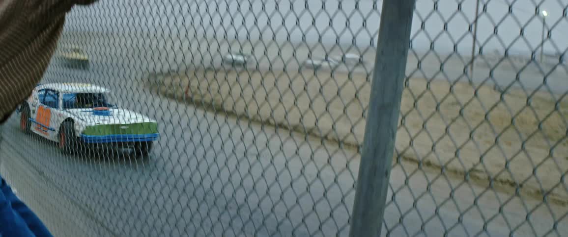 A man watches cars at a speedway
