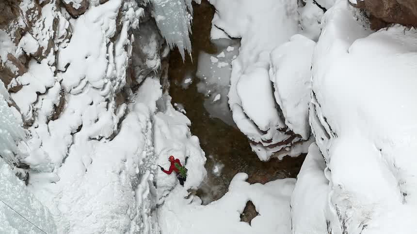 A man is brushing snow off of rocks below
