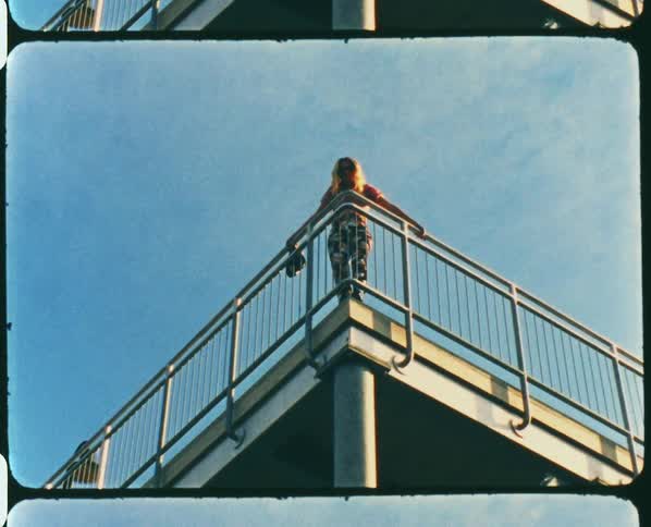 A woman leans on the railing on the platform