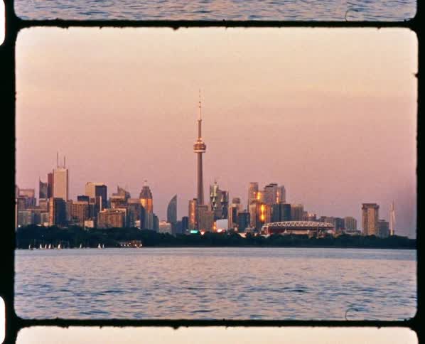 Skyline of a modern waterfront city at sunset caught on vintage film